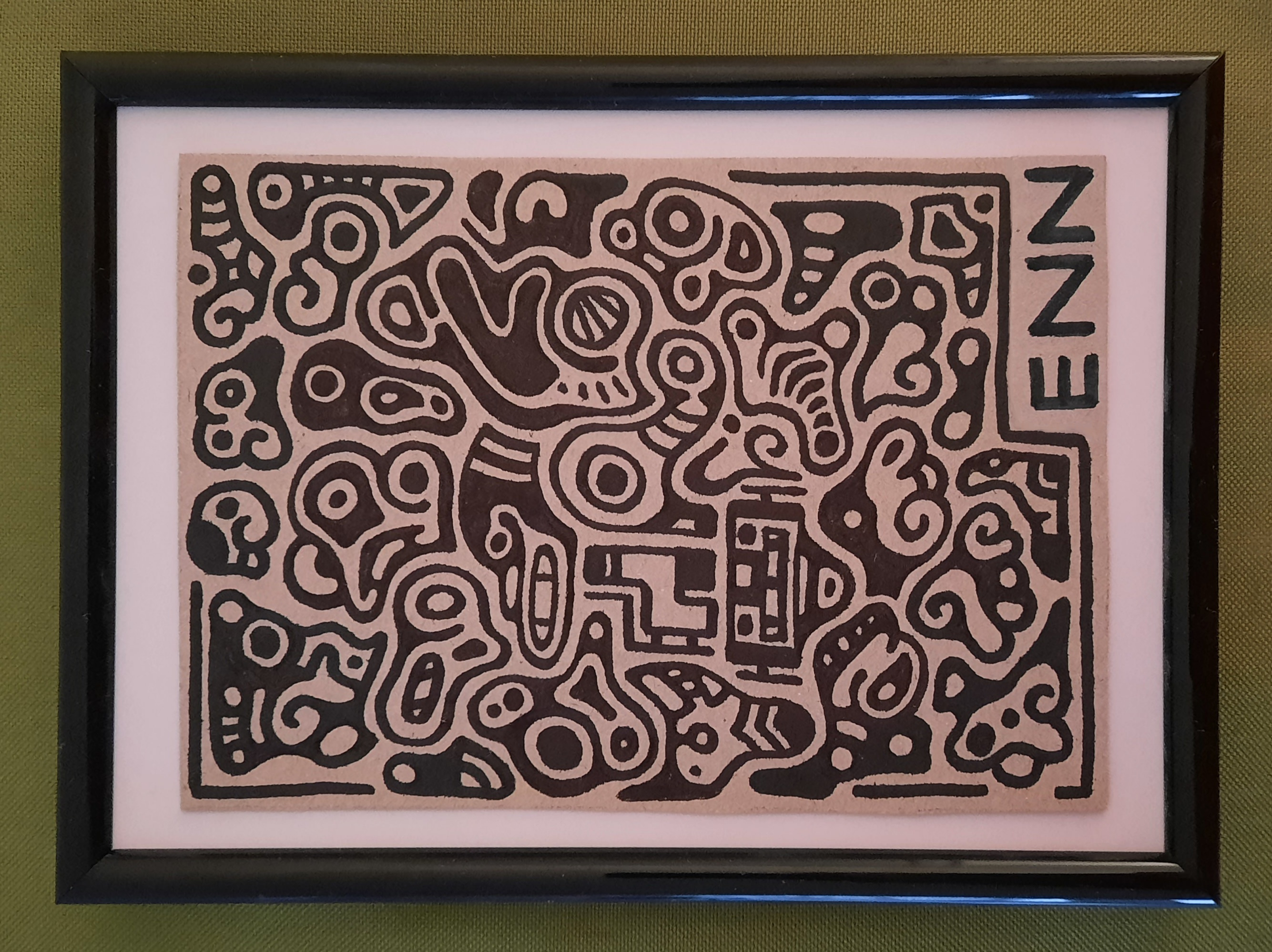 framed piece of cardboard covered in abstract doodles. it is signed ENN in the bottom corner.